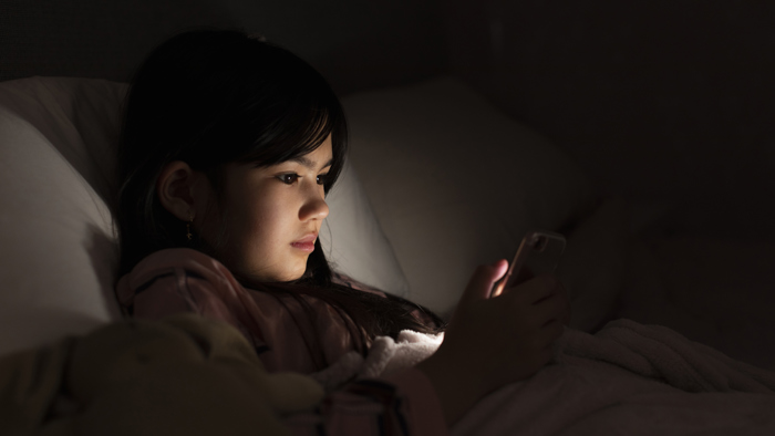 Flicka tittar in i sin mobil.